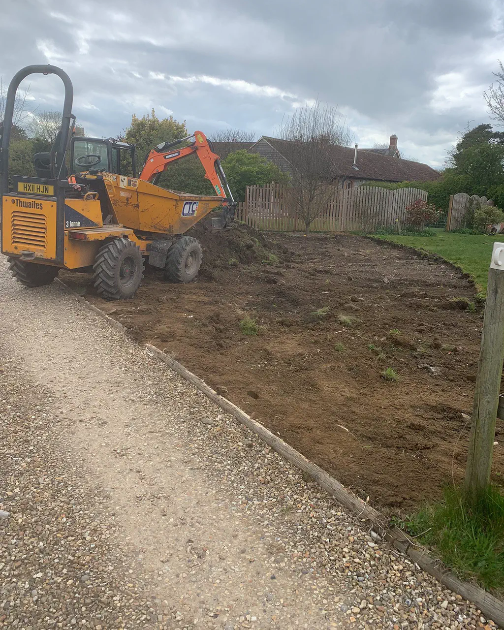 A site dumper and mini excavator on a levelled plot beside a gravel driveway
