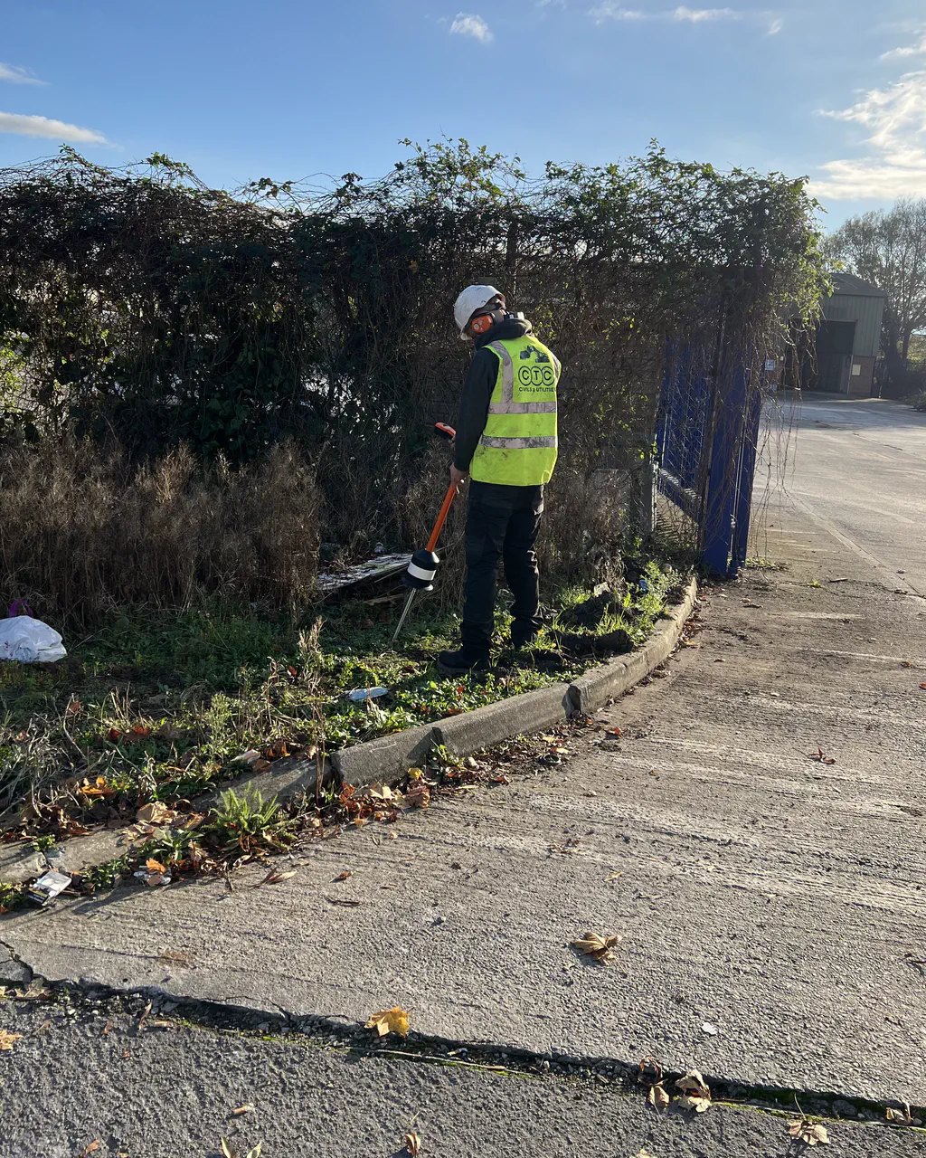 A CTC engineer in hi-vis and hard hat tracing a water leak along a kerbside verge