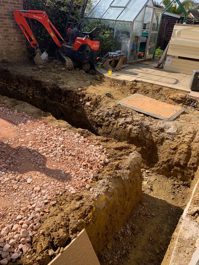 A deep foundation trench cut through stone and clay